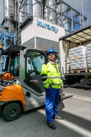 Kuraray Europe GmbH employee wearing blue work pants, yellow jacket and blue safety helmet.