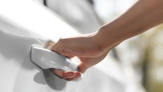 Hand on the door handle of a white car.